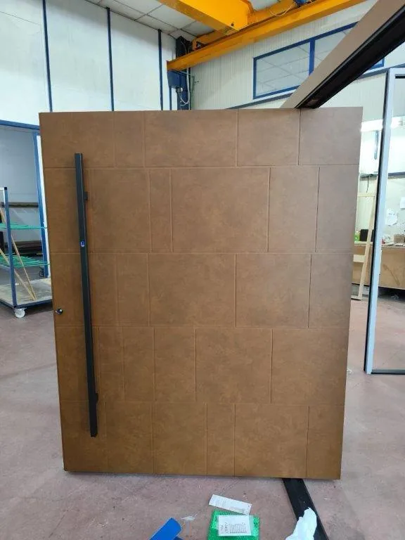 Porte d’entrée pivot aspect corten (acier rouillé) avec longue barre de tirage noire