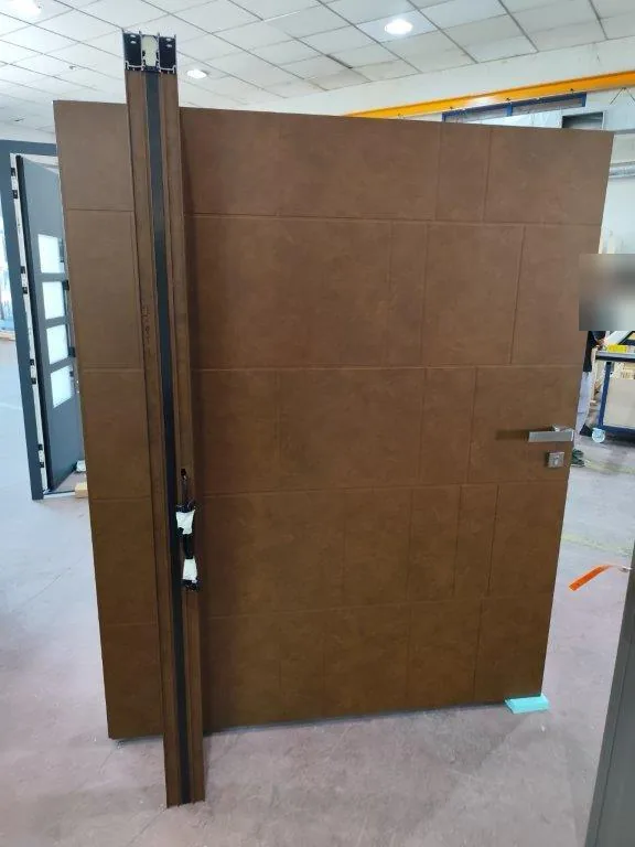 Face intérieure d’une porte pivot aspect corten avec poignée inox